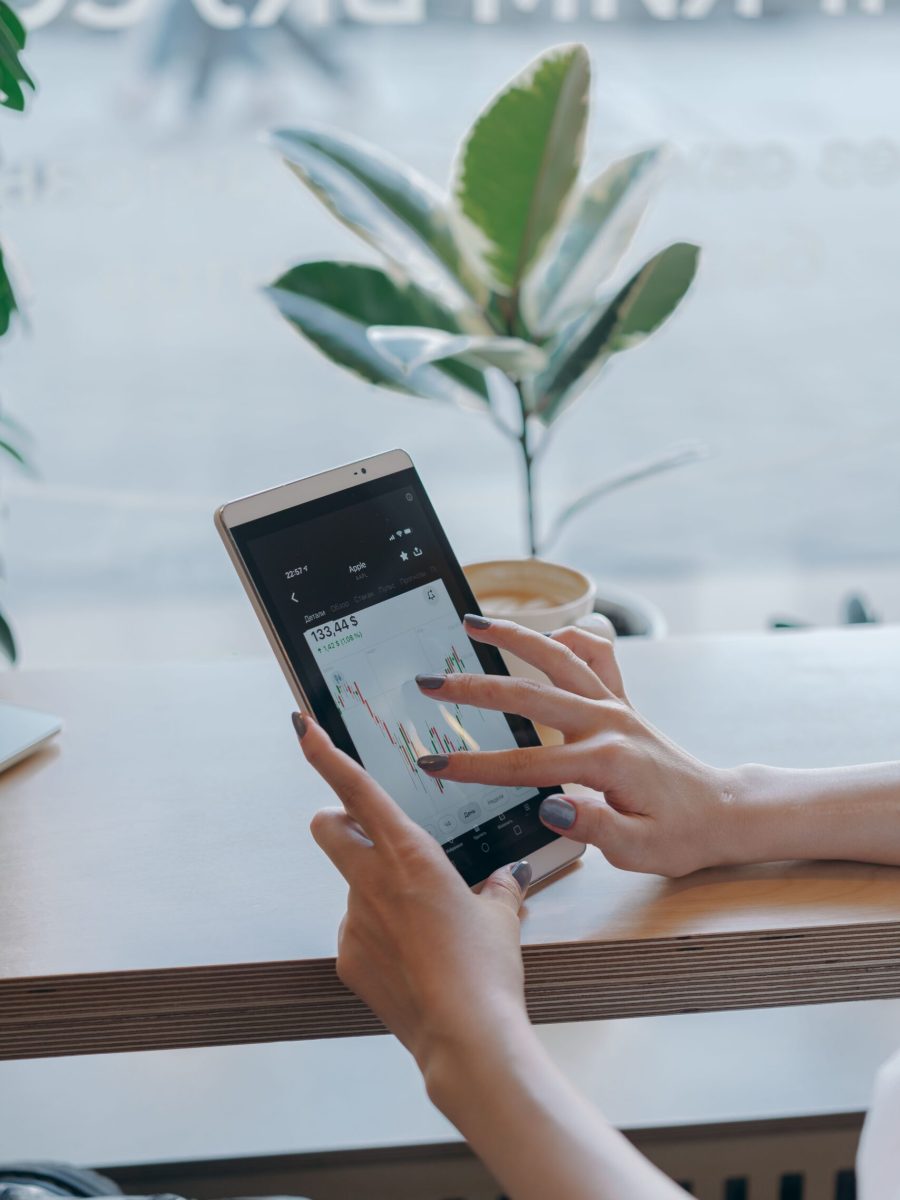 Person using a tablet to analyze stock market graphs, symbolizing remote work and finance.